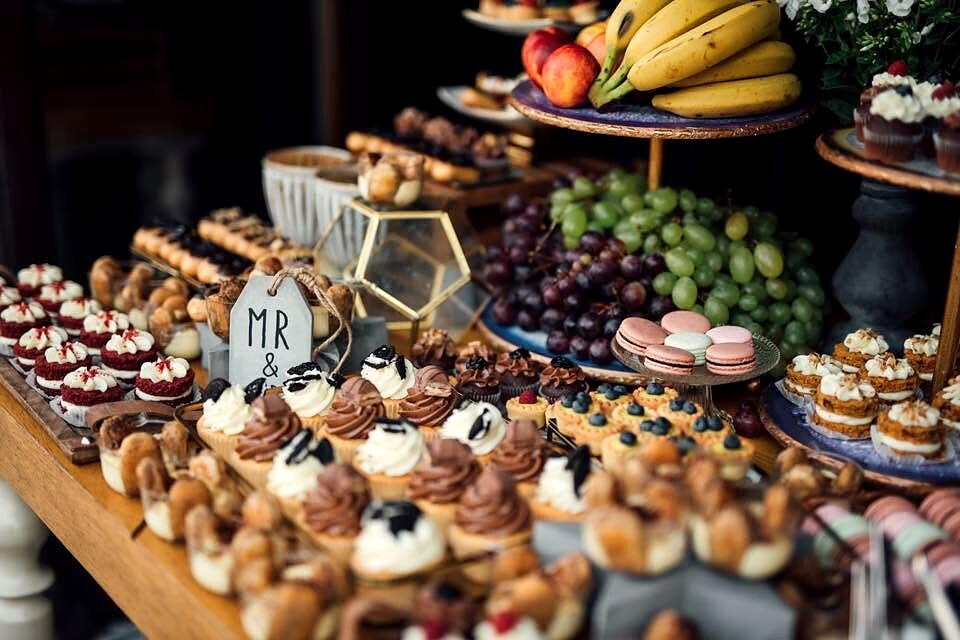 Masă de deserturi la nuntă, cu tartelete, macarons și fructe