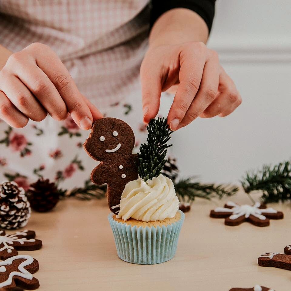 Omuleț de turtă dulce așezat cu mâna pe un cupcake